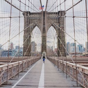 Rear view of man jogging on suspension bridge