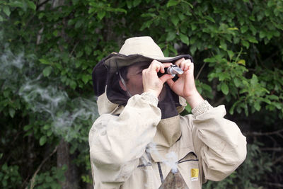 Full length of man photographing against trees