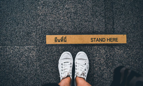 Low section of man standing on road sign