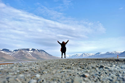 Rear view of man standing on land against sky