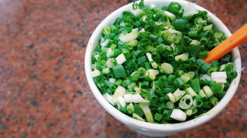 High angle view of chopped scallion in bowl on marble
