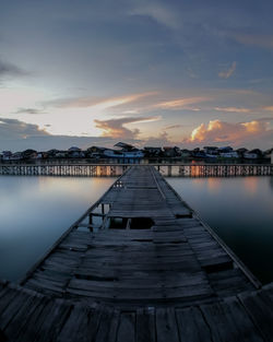 Pier over lake against sky during sunset