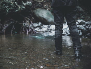 Low section of man standing on wet land