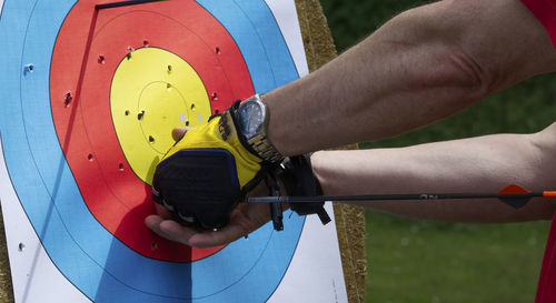 Cropped hands of man removing arrow from target