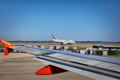 Airplanes at runway against blue sky