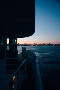 Buildings by sea against clear sky during sunset