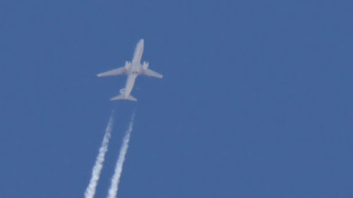 Low angle view of airplane flying against clear blue sky