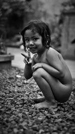 Portrait of cute naked girl crouching outdoors