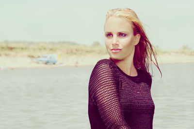 Portrait of beautiful young woman standing against sea