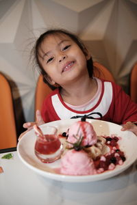 Portrait of a kid with strawberry ice cream in plate