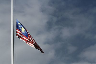 Low angle view of flag waving against cloudy sky