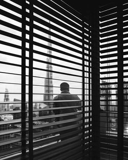 Rear view of man sitting on window