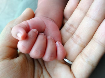 Close-up of parent holding baby hand