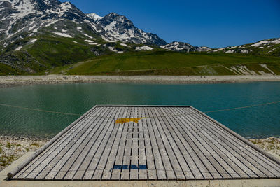 View of wooden ramp by lake against mountain