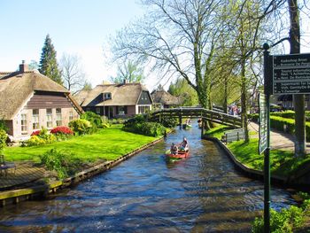 People on river amidst trees and buildings