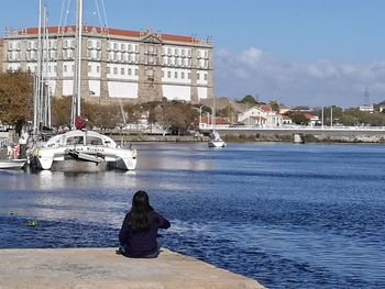 Rear view of woman sitting on boat against sky