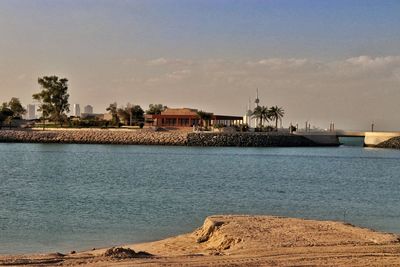 Buildings by sea against sky