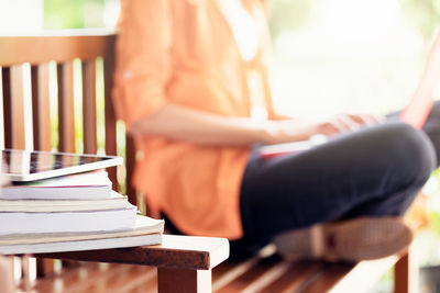 Stacked books by women sitting on bench