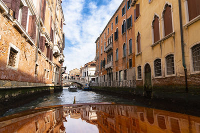 Canal amidst buildings in city against sky