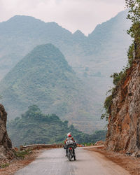 Rear view of man riding bicycle on mountain road