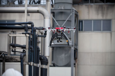 Professional red drone flying around in the outdoor of a factory.