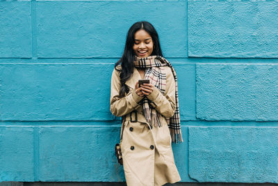 Smiling young woman standing against wall
