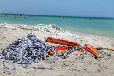 Close-up of rope on sand at beach against sky