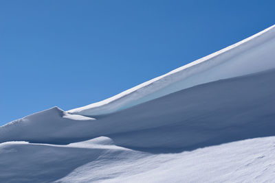 Low angle view of snow against blue sky