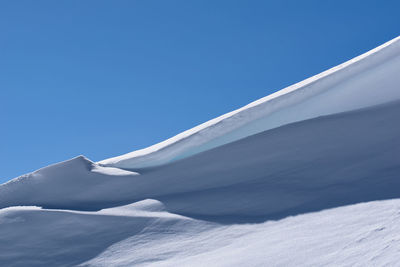 Low angle view of snowcapped mountain against clear blue sky