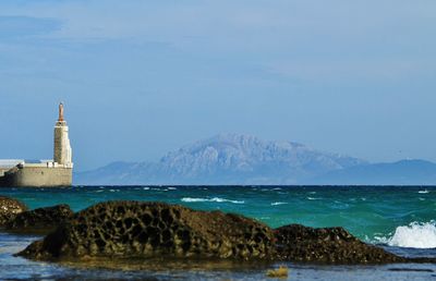 Scenic view of sea by buildings against sky