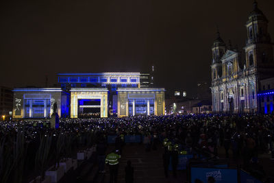 Crowd on illuminated building against sky at night