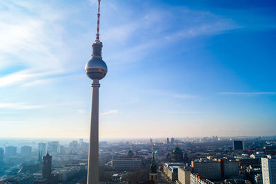 Communications tower in city against sky