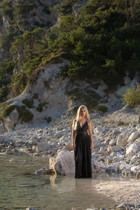 Woman standing on rock against waterfall