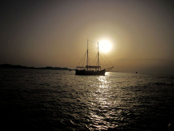 Lone boat in calm sea against bright sun
