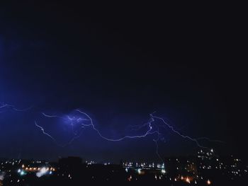 Low angle view of illuminated city against sky at night