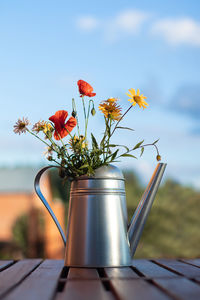 Close-up of flower vase on table against sky