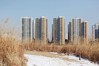 Panoramic shot of buildings on field against clear sky