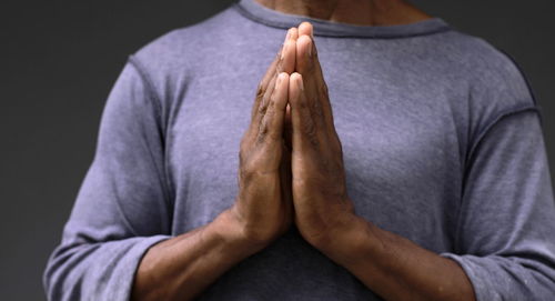 Black man praying to god on gray background with people stock image stock photo