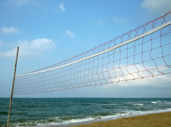 Volleyball net at beach against sky