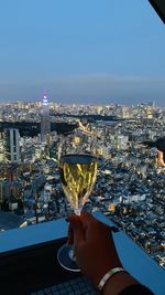 High angle view of man holding glass of buildings against sky