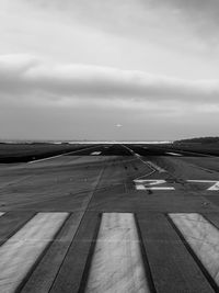 View of airport runway against cloudy sky