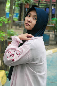 Portrait of smiling young woman standing in park