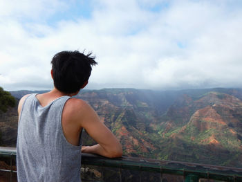 Rear view of woman looking at mountains against sky