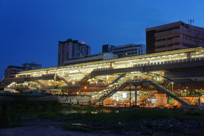 Low angle view of illuminated bridge against blue sky in city at dusk