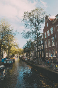 Canal amidst buildings in city against sky 