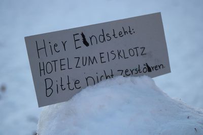 Close-up of text on snow against sky