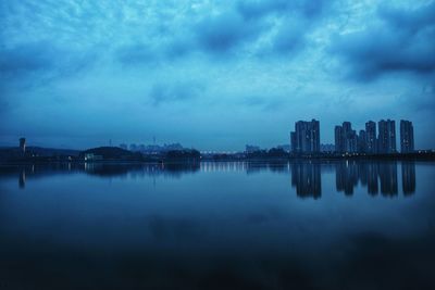 Scenic view of lake by buildings against sky at dawn