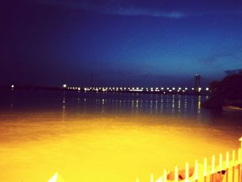 Illuminated bridge over river at night