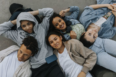 High angle view of smiling teenagers lying together and looking at camera