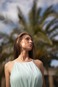 Portrait of young woman standing against trees